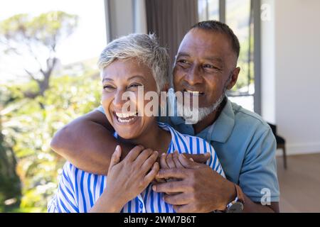 Couple biracial senior partage une étreinte joyeuse à la maison Banque D'Images