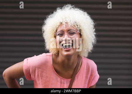 Jeune femme biraciale rit joyeusement dans la ville sur un fond rayé Banque D'Images