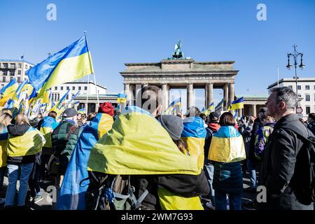 Berlin, Allemagne. 24 février 2024. Des manifestants drapés de drapeaux ukrainiens prennent part au rassemblement. Des milliers de manifestants en soutien à l'Ukraine se sont rassemblés à la porte de Brandebourg pour marquer les deux ans de l'invasion massive de l'Ukraine par la Russie. (Photo de Nicholas Muller/SOPA images/SIPA USA) crédit : SIPA USA/Alamy Live News Banque D'Images