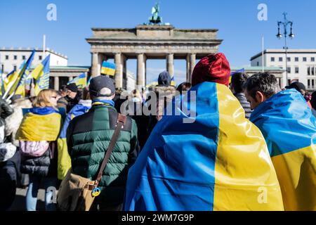Berlin, Allemagne. 24 février 2024. Des manifestants drapés de drapeaux ukrainiens prennent part au rassemblement. Des milliers de manifestants en soutien à l'Ukraine se sont rassemblés à la porte de Brandebourg pour marquer les deux ans de l'invasion massive de l'Ukraine par la Russie. (Photo de Nicholas Muller/SOPA images/SIPA USA) crédit : SIPA USA/Alamy Live News Banque D'Images