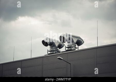 Conduits d'air métalliques sur le toit. Tuyauterie du système de ventilation devant le ciel nuageux. Banque D'Images