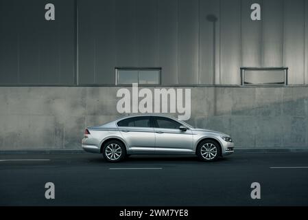 Berline Volkswagen Passat argentée garée devant le mur gris - vue latérale Banque D'Images