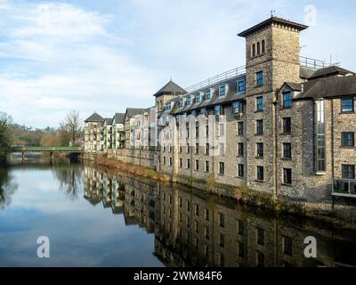 L'hôtel Riverside en pierre traditionnel et les appartements reflétant dans la rivière Kent sur une journée d'hiver ensoleillée et lumineuse avec Victoria Bridge derrière. Banque D'Images