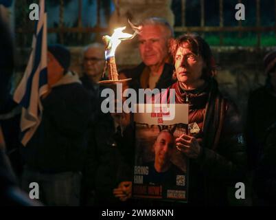 Jérusalem, Israël. 24 février 2024. Les participants à une manifestation appelant le gouvernement israélien à conclure un accord avec le Hamas, pour renvoyer les otages chez eux. Les personnages principaux sont une femme tenant une torche et une pancarte avec une photo d'un otage. À sa gauche se trouve le drapeau israélien. Crédit : Yoram Biberman/Alamy Live News. Banque D'Images