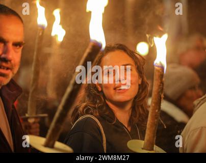 Jérusalem, Israël. 24 février 2024. Les participants à une manifestation appelant le gouvernement israélien à conclure un accord avec le Hamas, pour renvoyer les otages chez eux. La figure principale est une belle jeune fille souriante tenant une torche avec beaucoup de flammes et de fumée dans le cadre crédit : Yoram Biberman/Alamy Live News. Banque D'Images