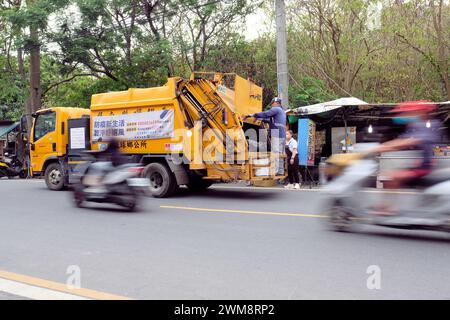 Camion à ordures collectant les ordures avec le travailleur à cheval sur la route de Zhongzhan comme scooters à moteur conduisent par ; Xiaoliuqiu, Taiwan ; collecte des ordures de la ville. Banque D'Images