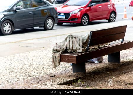 Salvador, Bahia, Brésil - 05 janvier 2024 : un sans-abri est vu dormir sur un banc en bois dans le quartier de Comercio dans la ville de Salvador, Ba Banque D'Images