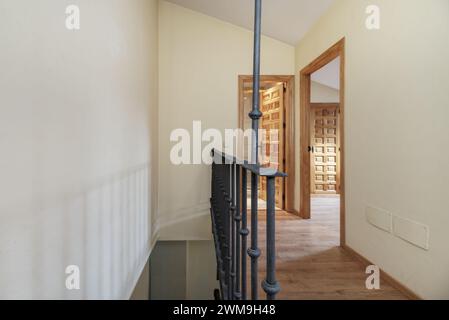 Escalier intérieur d'une maison résidentielle en duplex avec balustrades métalliques, portes en panneaux de bois de style castillan et planchers en bois Banque D'Images