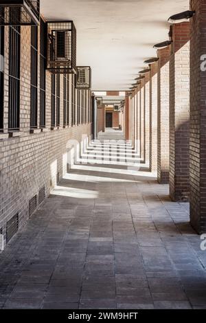 Passage au sous-sol d'un immeuble avec ombres des piliers, point de fuite et climatiseurs dans des cages métalliques Banque D'Images