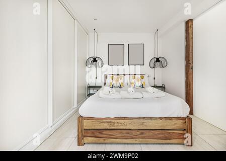 Chambre avec lit double avec structure en bois particulière, décoration actuelle et armoire intégrée d'un côté Banque D'Images