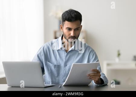 L'homme indien prépare l'accord, apprend les détails du contrat en travaillant sur ordinateur portable Banque D'Images