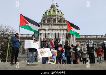 Harrisburg, États-Unis. 24 février 2024. Les travailleurs de la santé tiennent des pancartes et des drapeaux palestiniens lors du rassemblement des travailleurs de la santé pour la Palestine sur les marches du Capitole de l'État de Pennsylvanie. La Harrisburg Palestine Coalition ainsi que d'autres organisations, dont la Pittsburgh Palestine Coalition, Penn State Students for Justice in Palestine et Jewish Voice for Peace Philadelphia, ont organisé le rassemblement pour montrer leur solidarité avec les travailleurs médicaux à Gaza et pour appeler à un cessez-le-feu immédiat. Crédit : SOPA images Limited/Alamy Live News Banque D'Images