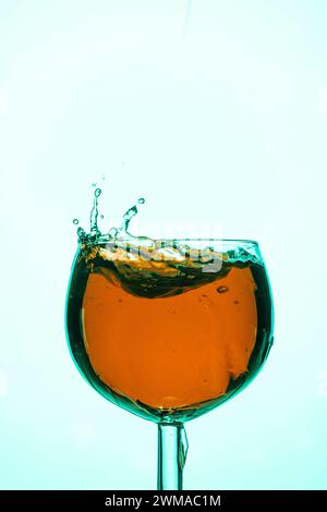 Des éclaboussures énergiques dans un verre à vin avec un liquide orange créent une scène dynamique Banque D'Images
