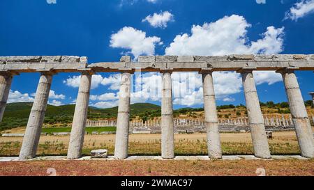 Ancienne rangée de colonnes partiellement reconstruite devant un stade antique, sous un ciel bleu, site archéologique, ancienne Messène, capitale de Banque D'Images