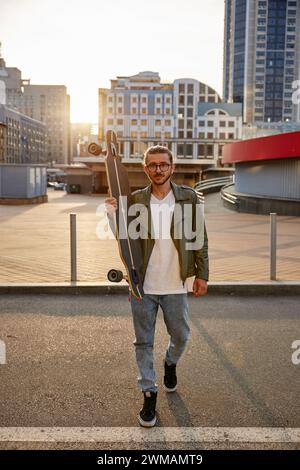 Portrait pleine longueur de skateboarder hipster Guy sur fond urbain Banque D'Images