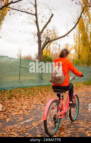 Fille sur le vélo dans le parc. Journée mondiale du vélo. Personnes actives. Loisirs actifs. Femme en vélo d'équitation orange Banque D'Images