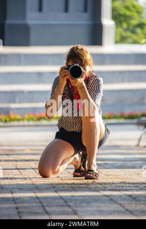 Belle fille prendre une photo à la rue. Paparazzi avec caméra. Hobby de photographie. Concept de reportage de rue. Concept d'entreprise photo. Capturez l'instant présent Banque D'Images