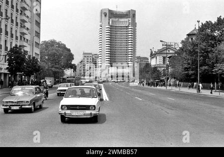 Bucarest, Roumanie, approx. 1980. Véhicules circulant sur le boulevard I.C. Bratianu à travers la place de l'Université, avec l'hôtel Intercontinental vu à l'arrière. Banque D'Images