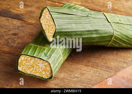 Tempeh cru enveloppé dans des feuilles de banane. Le tempeh est un aliment typiquement indonésien à base de soja fermenté et de plusieurs autres ingrédients Banque D'Images