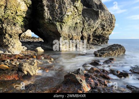 Grotte marine et rochers colorés sur la plage de Seaham Blast, Durham Heritage Coast, Seaham, comté de Durham, Royaume-Uni Banque D'Images