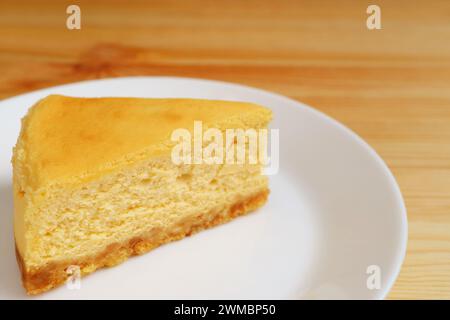 Tranche d'appétissant cheesecake cuit au four sur une assiette blanche Banque D'Images