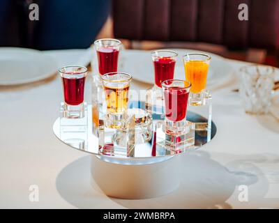 Ensemble de différents amers et liqueurs colorés dans des verres à injection sur la table du restaurant. Collection de tireurs. Sélection de teintures alcooliques naturelles de baies dans des verres. Différents amers et liqueurs Banque D'Images