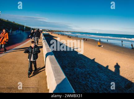 Promeneurs du soleil sur la plage de Whitley Bay en janvier Banque D'Images