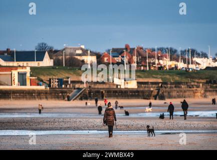 Promeneurs du soleil sur la plage de Whitley Bay en janvier Banque D'Images