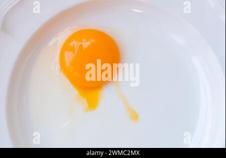 La nourriture crue d'œufs de poule sans coquille dans une assiette blanche est préparée pour la cuisson des aliments. Banque D'Images
