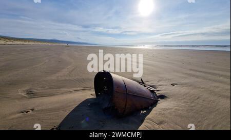 Les teintes chaudes du soleil couchant projettent une lueur sereine sur les dunes de Harlech Beach au pays de Galles, avec les collines lointaines créant une scène côtière tranquille Banque D'Images