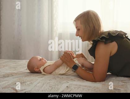 jeune mère avec son enfant joue et rit un jour ensoleillé à la maison Banque D'Images