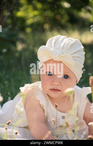 un petit enfant est allongé sur le ventre sur une couverture dans le jardin sur l'herbe, sur une promenade, Banque D'Images