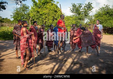 Un touriste occidental regarde un groupe de guerriers Massaï chanter et exécuter la danse traditionnelle du saut dans leur village de Mikumi, en Tanzanie Banque D'Images