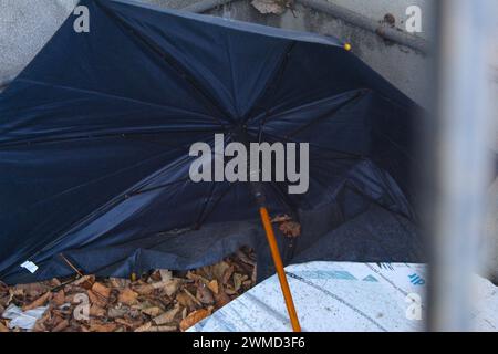 Dublin, Irlande - 24 février 2024 : une photo rapprochée d'un parapluie noir sur un tas de feuilles abandonnées et isolées. Banque D'Images