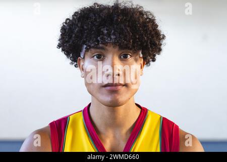 Jeune homme biracial dans un maillot de basket pose avec confiance Banque D'Images