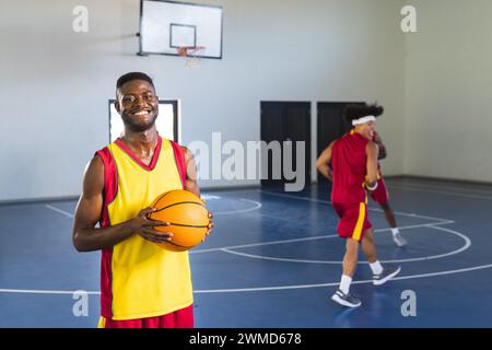 Homme afro-américain tient un basket dans un court intérieur, avec espace de copie Banque D'Images
