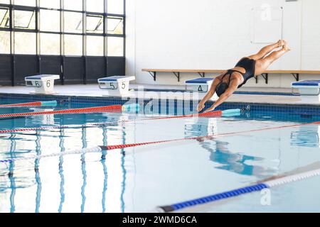 Athlète nageuse caucasienne plonge dans une piscine dans un centre sportif Banque D'Images