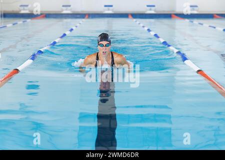 Une athlète nageuse caucasienne nage dans une piscine intérieure Banque D'Images