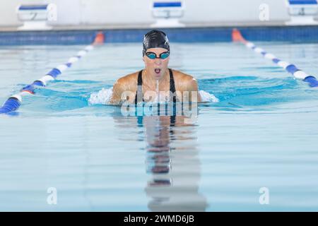 Une athlète nageuse caucasienne nage dans une piscine intérieure Banque D'Images