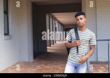 Adolescent biracial garçon se tient confiant au lycée, avec un espace de copie Banque D'Images