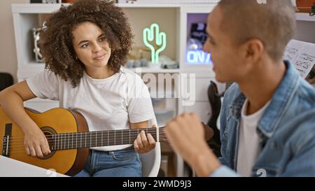 Des musiciens confiants chantent joyeusement et strumentent des chansons classiques sur une guitare espagnole, rayonnant de bonheur dans un studio de musique d'intérieur animé Banque D'Images