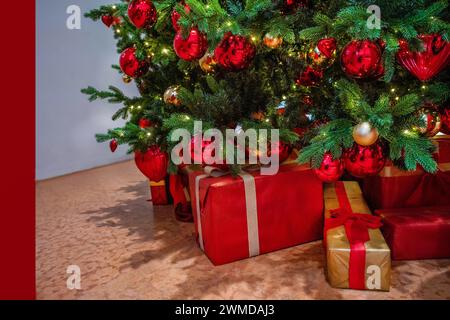 Cadeaux de Noël fantastiques (boîtes avec rubans) à l'arbre de Noël donné par le Père Noël et lumières de Noël et boules sur l'arbre Banque D'Images