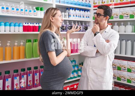 Homme et femme pharmacien et cliente enceinte parlant à la pharmacie Banque D'Images