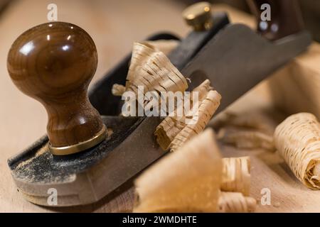 Photo horizontale gros plan d'un avion antique à la main sur une surface en bois, entouré de copeaux de bois délicats, mettant en valeur l'artisanat fin. Busines Banque D'Images