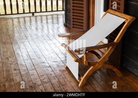 Chaise pliante en bois vacante avec siège en tissu blanc se dresse sur la terrasse Banque D'Images