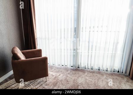 Confortable fauteuil de luxe se tient dans une pièce vide devant la fenêtre panoramique par une journée ensoleillée Banque D'Images