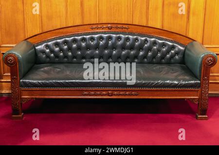 Canapé vintage de luxe avec siège en cuir véritable vert et base en bois décorée de sculpture sur tapis rouge Banque D'Images