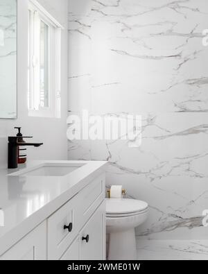 Salle de bain blanche et lumineuse avec murs en marbre et un lavabo avec robinet noir Banque D'Images