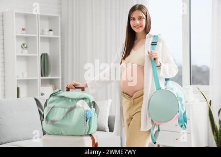 Jeune femme enceinte avec sacs d'hôpital de maternité emballés à la maison Banque D'Images