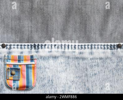 Fond denim gris et gris clair avec couture et poche colorée. Texture de tissu Jean denim de couleur gris clair et pochette multicolore rayée. Copier Banque D'Images